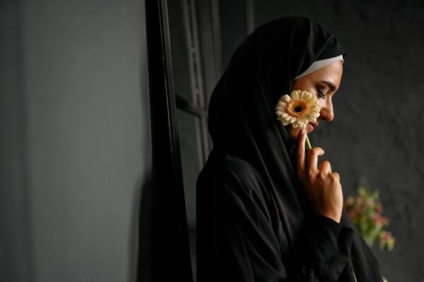 woman in black hijab holding a flower