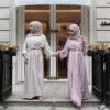 two women wearing dresses standing on a porch, abaya buy