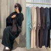 a woman taking a selfie in front of a rack of clothes, dress for hijab