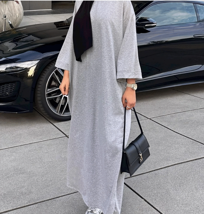 a woman wearing a grey dress and a black purse, dress abaya,