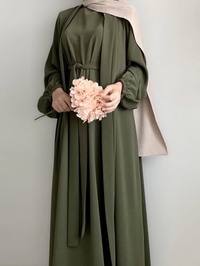 a woman in a green dress holding a pink flower, abaya women