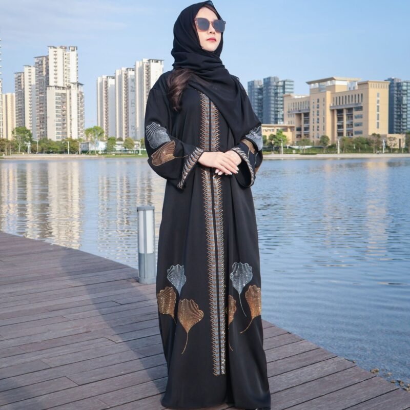 a woman wearing a black dress and sunglasses standing on a dock near water,
abaya dresses