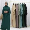 a woman standing in front of a rack of clothes, plus size abayas