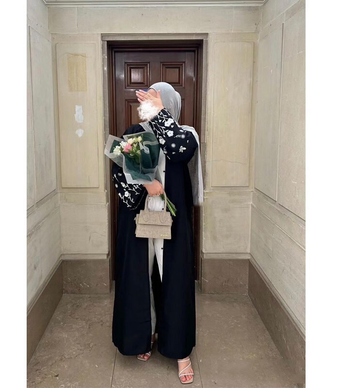 a woman in a black dress holding flowers and a purse,dresses for hijab